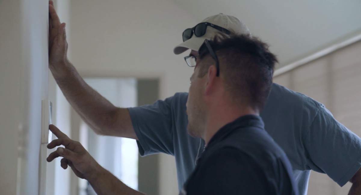 Technician explaining air conditioning touch panel to customer