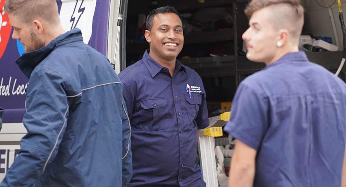 Technicians smiling in front of van